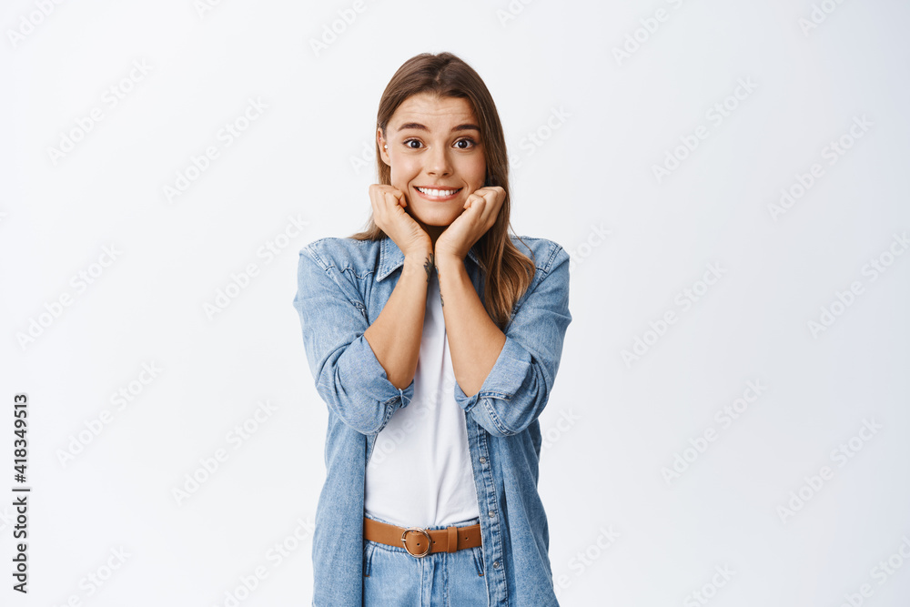 Beautiful young woman looking hopeful and smiling at camera, biting lip excited, staring at interesting promo, waiting with temptation, standing against white background Beautiful young woman looking hopeful and smiling at camera, biting lip excited, staring at interesting promo, waiting with temptation, standing against white background