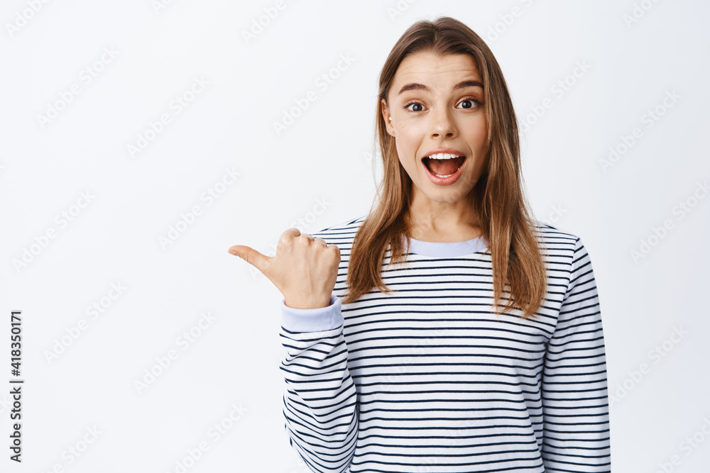 Amazed blond woman talking about promo offer with excitement, looking impressed and pointing left, asking to take look and check out banner, white background Amazed blond woman talking about promo offer with excitement, looking impressed and pointing left, asking to take look and check out banner, white background