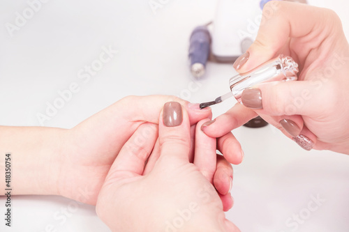 Applying the gel to the nail plate in a beauty salon.