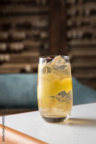 Highball cocktail with lemon peel, anise and ice on the table at restaurant
