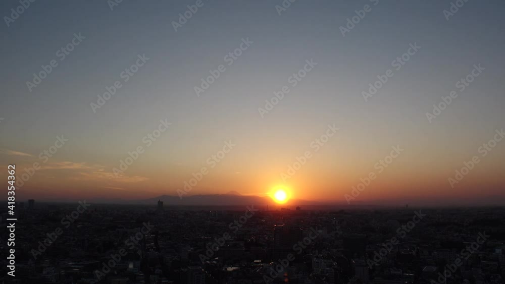 TOKYO, JAPAN : Aerial high angle sunset CITYSCAPE of TOKYO and MOUNT FUJI. View of sinking sun and buildings. Japanese urban city life and metropolis concept. Time lapse zoom in shot dusk to night. TOKYO, JAPAN : Aerial high angle sunset CITYSCAPE of TOKYO and MOUNT FUJI. View of sinking sun and buildings. Japanese urban city life and metropolis concept. Time lapse zoom in shot dusk to night.