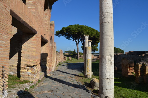Panorama of ancient Roman ruins house with street trees sun and blue sky