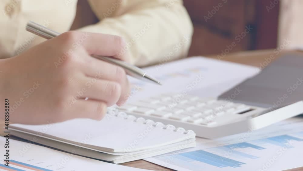 Presses a calculator button to calculate, Write down information in a notebook, Working in a private room during the virus pandemic, Social distance. Presses a calculator button to calculate, Write down information in a notebook, Working in a private room during the virus pandemic, Social distance.