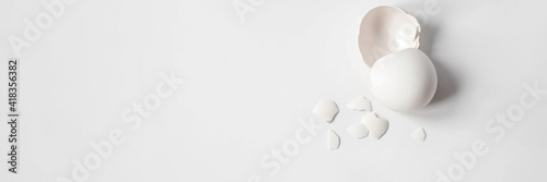 White eggshell of a broken chicken egg with shards isolated on a white background. Easter.View from above.Banner photo