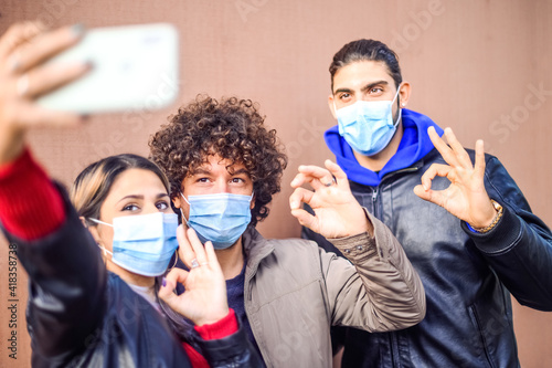 Self portrait of happy positive friends shooting selfie on front camera showing ok, like sign with fingers - New normal lifestyle concept about happy students in pandemic time