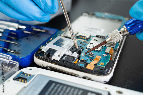 Technician repairing inside of mobile phone by soldering iron. Integrated Circuit. the concept of data, hardware, technology.