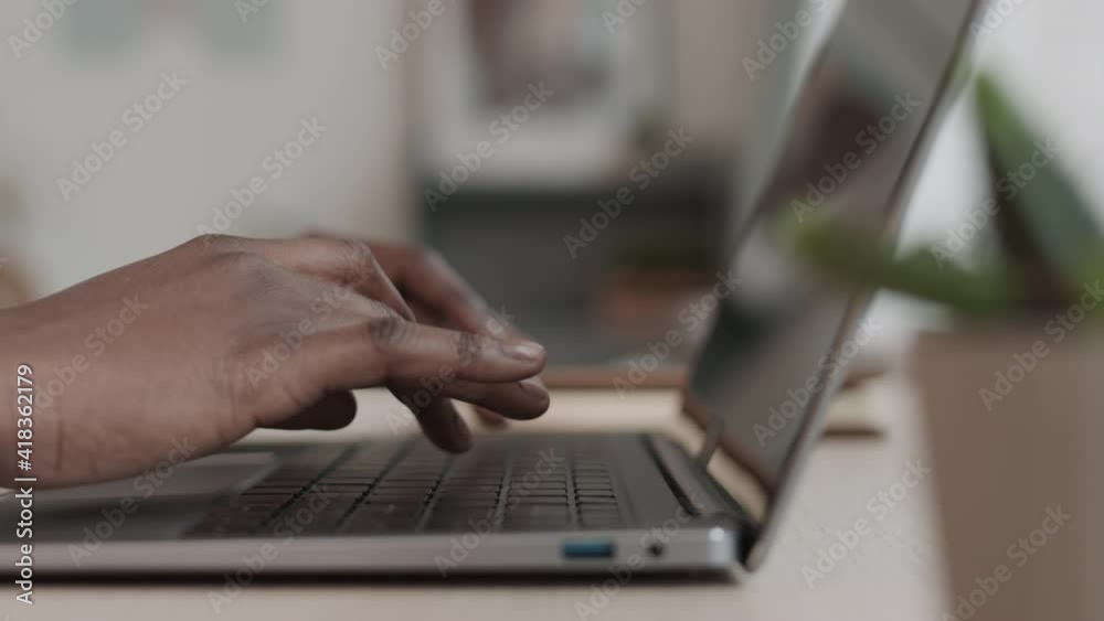 Close up of hands of unrecognizable African-American woman typing on laptop keyboard
