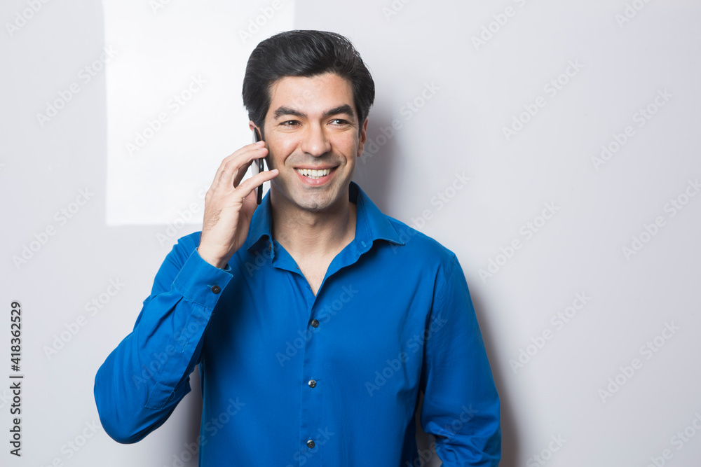 uomo moro in camicia blu parla al cellulare con espressione felice, isolato su sfondo su sfondo bianco uomo moro in camicia blu parla al cellulare con espressione felice, isolato su sfondo su sfondo bianco