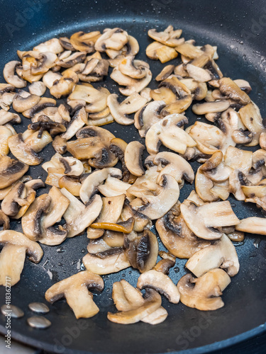 Close up of fried cut mushrooms in pan, top view.