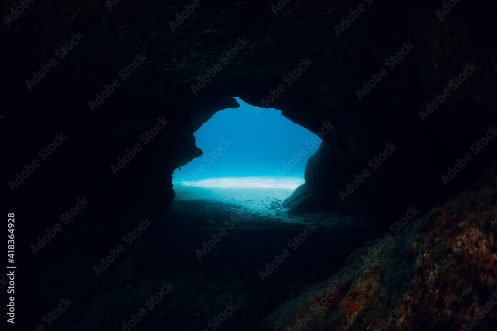 Underwater scene with cave in blue ocean