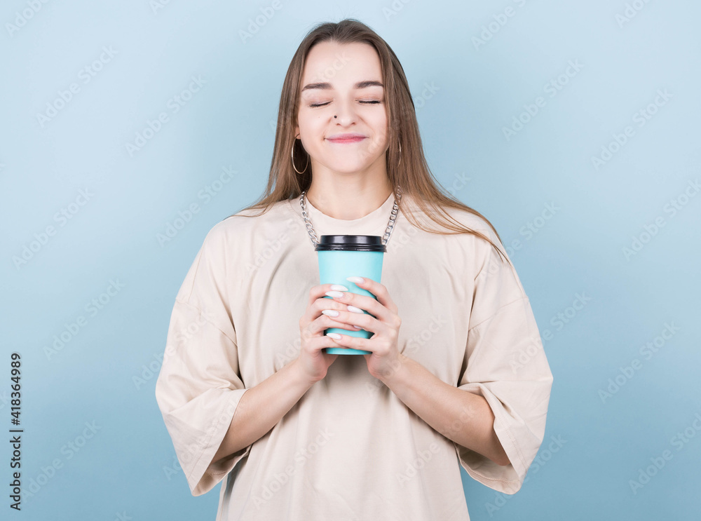 Photo of cheerful positive pretty girlfriend holding a cup of takeaway coffee smiling with closed eyes isolated on bright colored background Photo of cheerful positive pretty girlfriend holding a cup of takeaway coffee smiling with closed eyes isolated on bright colored background