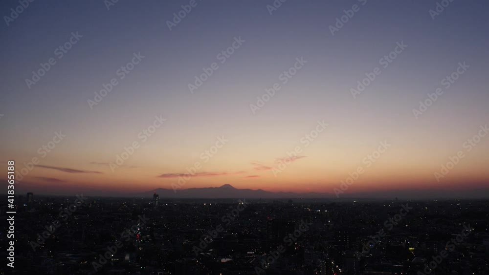 TOKYO, JAPAN : Aerial high angle sunset CITYSCAPE of TOKYO and MOUNT FUJI. View of sinking sun and buildings. Japanese urban city life and metropolis concept. Time lapse zoom out shot dusk to night. TOKYO, JAPAN : Aerial high angle sunset CITYSCAPE of TOKYO and MOUNT FUJI. View of sinking sun and buildings. Japanese urban city life and metropolis concept. Time lapse zoom out shot dusk to night.