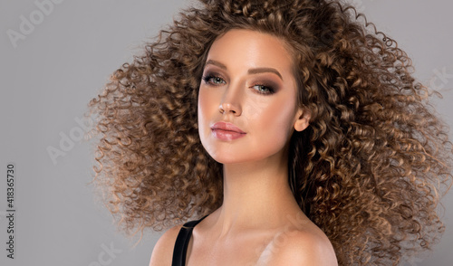 Brunette girl with long and shiny curly hair . Beautiful model woman with wavy hairstyle	 photo