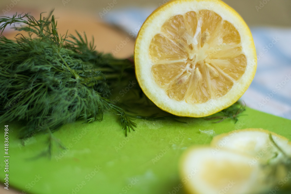 Sliced lemon on a green board with dill Sliced lemon on a green board with dill