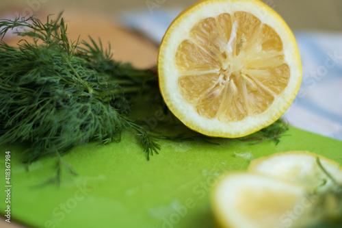 Sliced ​​lemon on a green board with dill
