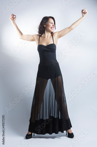 Figura intera di  ragazza mora con un abito nero con la gonna trasparente mettendo in mostra i muscoli con rabbia , isolata su sfondo bianco photo