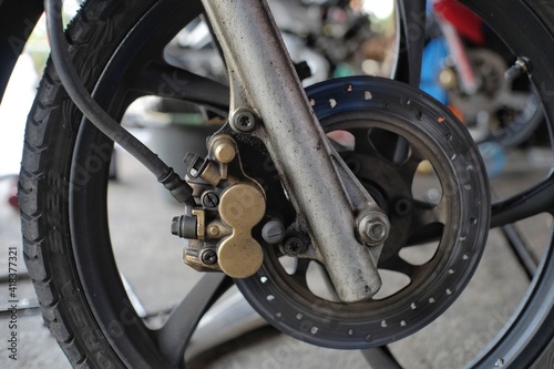 Oil-stained disc brakes on the front wheels of a motorbike