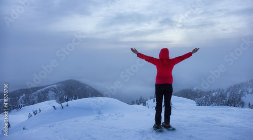 Adventure Girl With Snowshoes Hiking on top of the Mountain with Canadian Nature Landscape View in Background. Winter sunset. Taken in Seymour Mountain, North Vancouver, British Columbia, Canada. © edb3_16