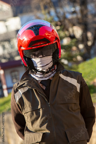 Armed man wearing a red motorcycle helmet. © satiozdemir