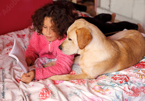 A child with a dog on the bed.