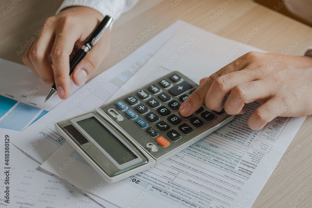 Close up hand of stress young asian businessman,male is pressing a calculator to calculate tax income and expenses, bills, credit card for payment or payday at home, office.Financial, finance concept. Close up hand of stress young asian businessman,male is pressing a calculator to calculate tax income and expenses, bills, credit card for payment or payday at home, office.Financial, finance concept.