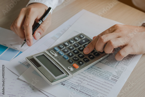 Close up hand of stress young asian businessman,male is pressing a calculator to calculate tax income and expenses, bills, credit card for payment or payday at home, office.Financial, finance concept.