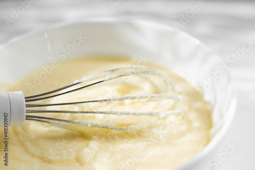 Cream whipped with mixer in a plate on a white background. Close-up cake cream. Light rays fall on the table