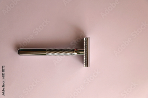 Reusable metal safety razor on pink background. Top view. photo