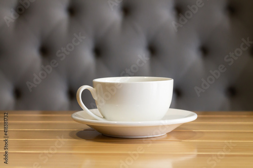 White cup and saucer on wooden table in living room interior