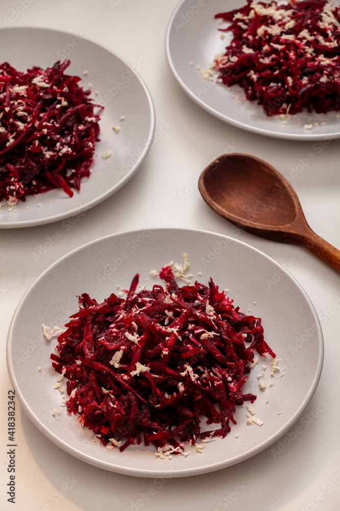 Grated baked beetroot and grated raw horseradish salad on a gray plate. Grated baked beetroot and grated raw horseradish salad on a gray plate.