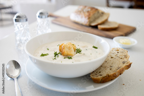 Bowl of Clam Chowder with Whole Grain Bread on a White Kitchen Counter