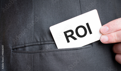Card with ROI text in pocket of businessman suit. Investment and decisions business concept.