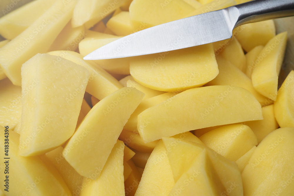 Top view of sliced fresh raw potatoes into pieces with a knife, background with ingredient for cooking Top view of sliced fresh raw potatoes into pieces with a knife, background with ingredient for cooking