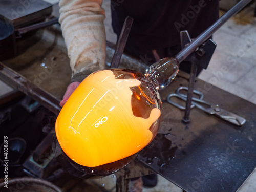 Glass artis shaping manualy big hot glass piece on glassblowing whistle