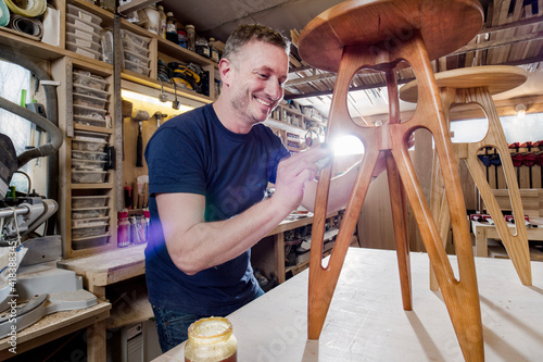Craftsman polishing wooden stool with oil finish