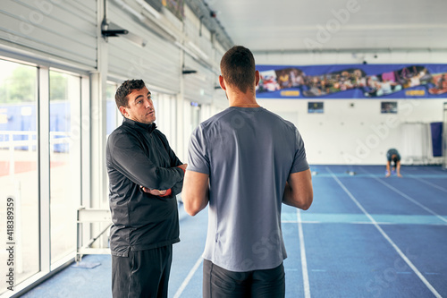 Coach and runner speaking in indoor running track photo