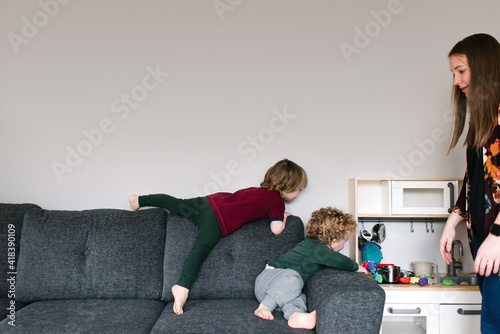 Mother watching over sons playing on sofa photo