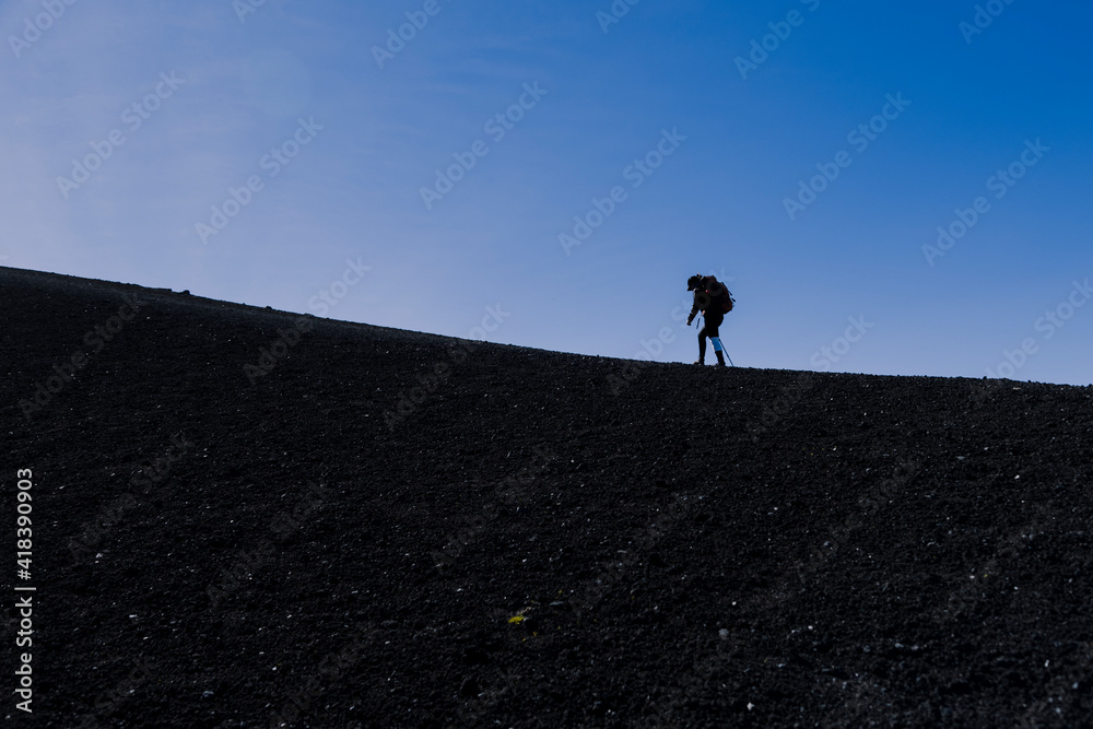 Climber with her backpack walking along the shore of the Acatenango volcano in Guatemala-woman hiker climbing the mountain-concept of effort and achievement of goals