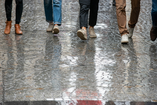 Young people walking on rainy cobblestone pavement