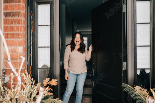 Mid adult woman opening house front door, portrait