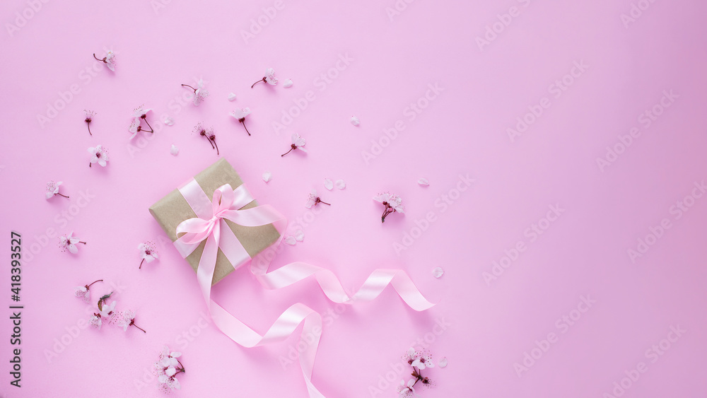 Cherry blossom and gift box with pink ribbon on pink background. Web banner image with copy space