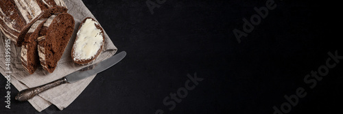 Obraz na płótnie Freshly baked homemade artisan sourdough rye and white flour bread. Sliced. Bread and butter and vintage table knife on dark background. Banner. Copy space. w salonie