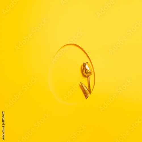 golden tulip in the frame of easter egg on sunny summer yellow background. minimal flat lay. abstract art