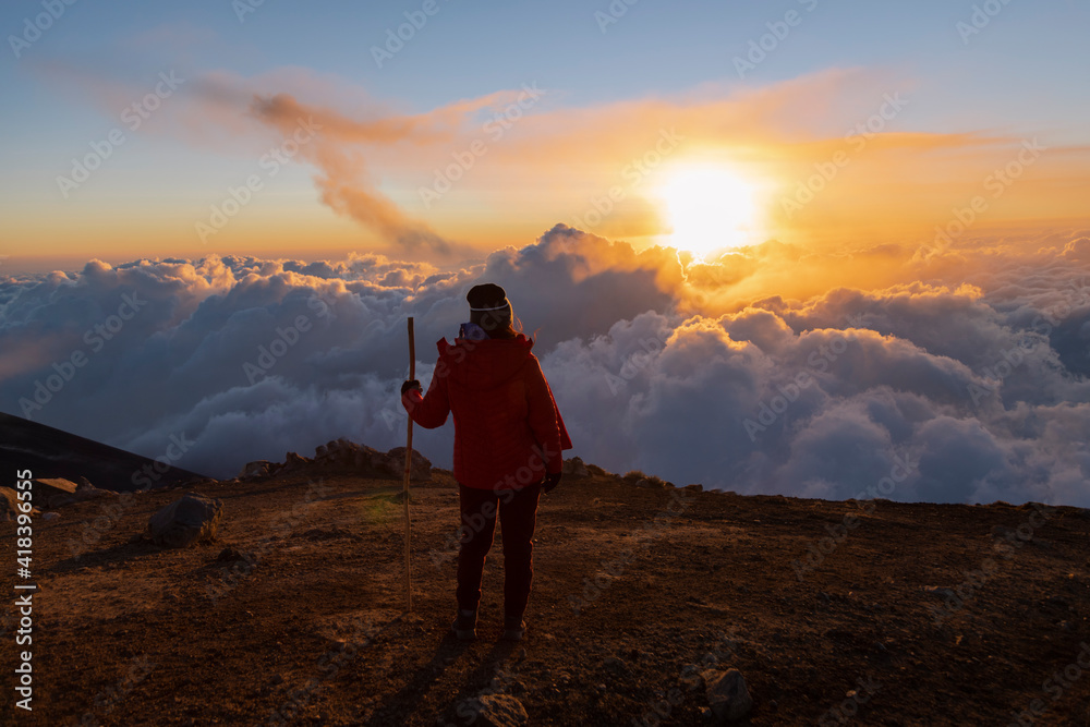 Young climber on top of the Acatenango volcano in Guatemala watching the sunset - woman hiking enjoying the sunset