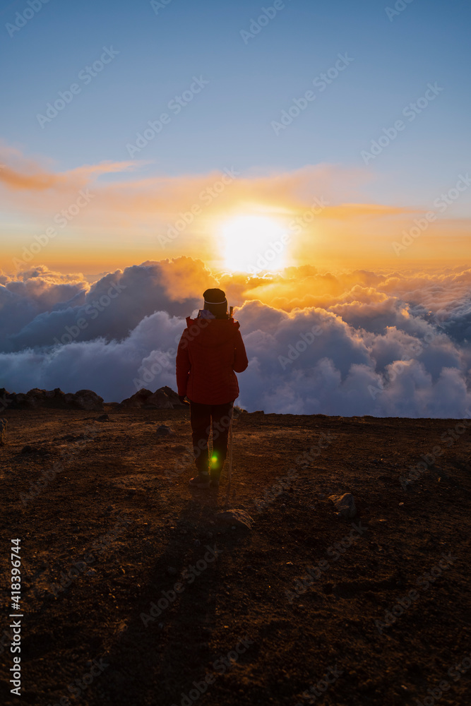 Climber on top of Acatenango volcano in Guatemala watching the sunset - woman hiking on top of the volcano at sunset