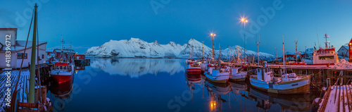 : A quiet afternoon in the harbor with ships in a fishing village, where in the background you can see the peaks of the mountains and bridges linking the islands in Lofoten photo