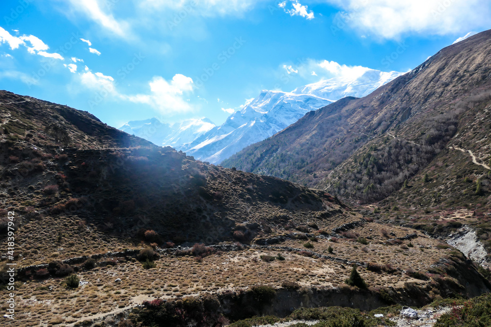 Harsh slopes of Manang Valley, Annapurna Circus Trek, Himalayas, Nepal, with the view on Annapurna Chain and Gangapurna. Dry and desolated landscape. High, snow capped mountain peaks. Freedom