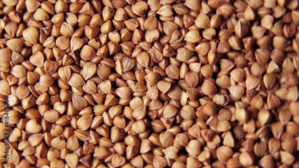 A close-up of a large amount of small brown buckwheat spinning on a plate. Healthy food concept A close-up of a large amount of small brown buckwheat spinning on a plate. Healthy food concept