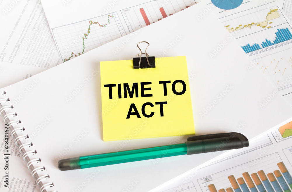 A yellow sticker with text Time To Act is in a Notepad with a green pen financial charts and documents A yellow sticker with text Time To Act is in a Notepad with a green pen financial charts and documents