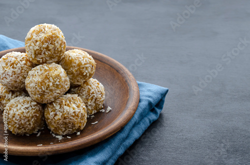 home made nutritional energy balls consisting of nuts, oatmeal, honey, dried fruits on a clay plate on a dark black slate background with a blue towel with place for text. healthy snack
